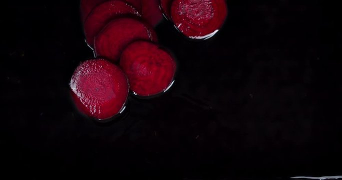 Pieces of fresh beets fall into the water.