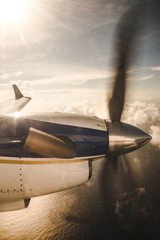 Small propeller plane flying over clouds to an island in the Caribbean Sea