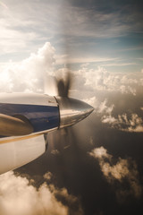 Small propeller plane flying over clouds to an island in the Caribbean Sea