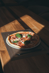 Fresh pizza on table under sunlight on restaurant background in the afternoon in the shade