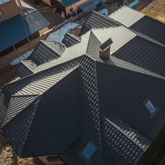 new roof, dark metal tile on a background of land, structure, construction brick house house, quadcopter shooting