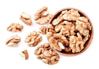 Walnut peeled in a wooden plate and scattered on a white background. The view fromtop.