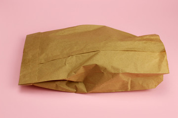 Kraft paper bag with food on pink background