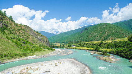 The panoramic view of deep valley, green mountains, floating Tsang river, and bank from the longest suspension bridge swinging over the Tsang river in Punakha