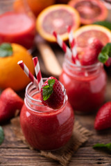 Strawberry smoothie in glass jar, over old wood table.