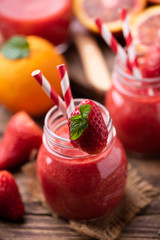 Strawberry smoothie in glass jar, over old wood table.