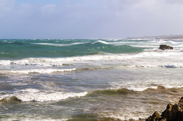 Beach between rocks on stormy day with lots of wind and waves, V