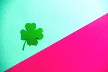 one green clover on a blue and rose background, flat lay, copy text.