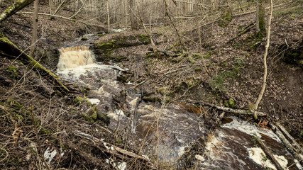 dirty waterfall on a small river in forest