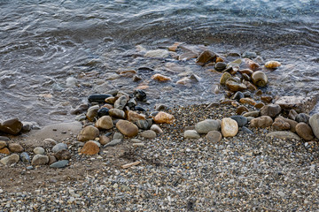 Fototapeta na wymiar Large and smooth stones in the coastal waves of salty sea water. The coast of the black sea foams and roars, beating against a huge pebble, illuminated by sunlight