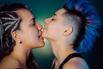 Young ethnic millennial woman kissing her lesbian punk girlfriend. Love is love. Freedom of choice, same gender partner. Fight for homosexual rights. Lgbt , gay pride, bisexual and androgynous people.