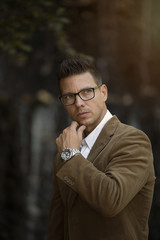 hombre apuesto modelo con gafas reloj en fondo parque desenfocado