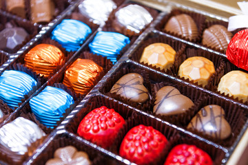 Chocolates in a box. Sweets are of various shapes and wrapped in a foil of different colors