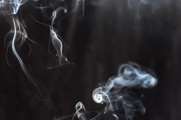 Image of backlit puffs of smoke, on a dark background.