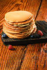 Stack of pancakes with berries.Copy space for your text. On a light brown background.