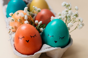 Colored Easter eggs in tray with funny or cute faces,