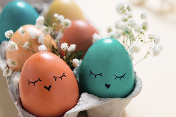 Colored Easter eggs in tray with funny or cute faces,