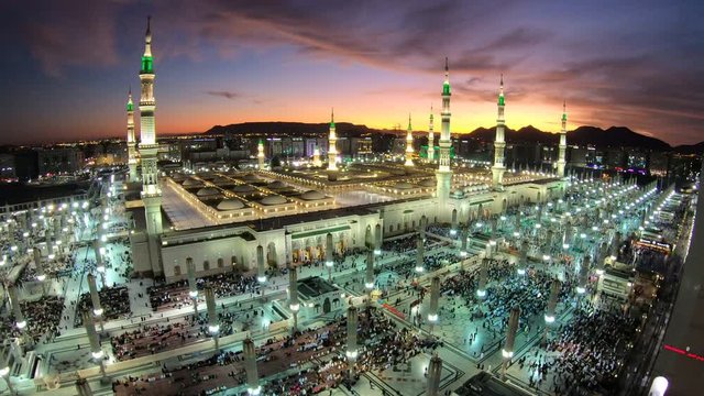 Time lapse of pilgrims performing prayer in illuminated Prophet's Mosque in Medina at sunset, Islam religion and stunning architecture in Saudi Arabia