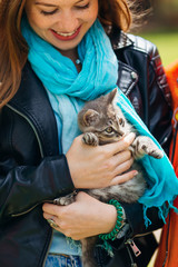 Obraz premium A stylish girl with freckles and a make-up holds a cat in her ar