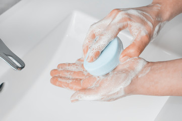 Hand washing techniques: woman soaping her hands with a bar of soap.