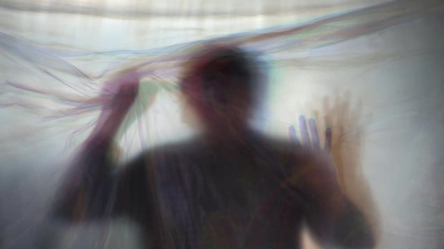 Paranoia concept, man behind plastic curtain