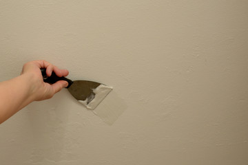 Woman plasterer repairing the wall with putty, copy space.
