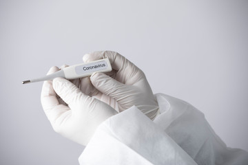 termometro con su scritto Coronavirus, tenuto da una mano con guanto su sfondo bianco