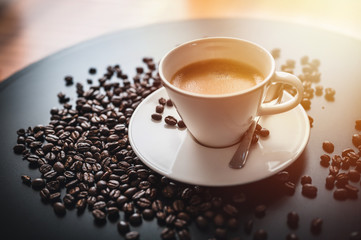 Coffee and coffee beans on black table.  Coffee beams closeup. Coffee theme. White cup on black table.