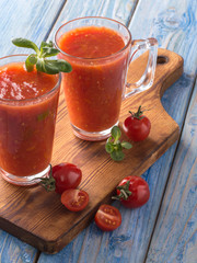 tomato juice in a glass cup on a wooden board.
