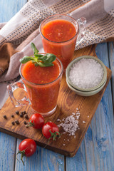 tomato juice in a glass cup on a wooden board.