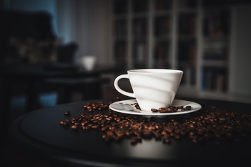 Coffee and coffee beans on black table.  Coffee beams closeup. Coffee theme. White cup on black table.