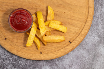 French fries with ketchup on wooden background, top view