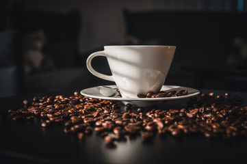Coffee and coffee beans on black table.  Coffee beams closeup. Coffee theme. White cup on black table.
