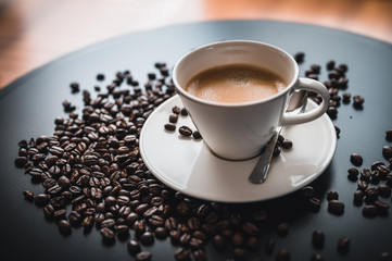 Coffee and coffee beans on black table.  Coffee beams closeup. Coffee theme. White cup on black table.