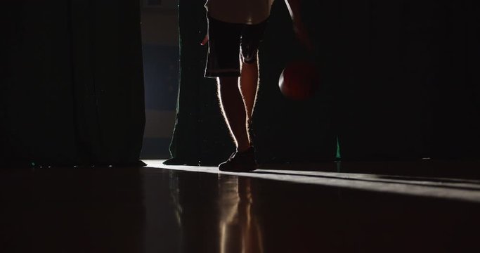 Young Caucasian basketball player getting ready to spin the ball on his finger. Bright light. Shade. Trick. Professional dribbling. Training. Back view.