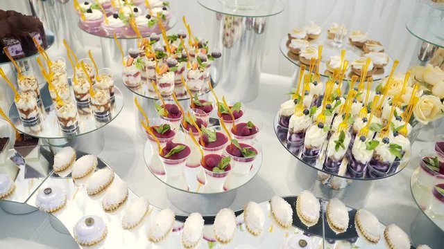 Rows of delicious decorated catering banquet table with different sweet food snacks and appetizers on corporate christmas birthday party event or wedding celebration. Wedding candybar. 