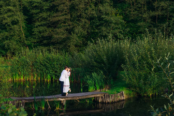 couple in embroidered clothes hugging on a wooden pier of a lake