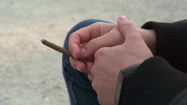 Male hands holding a cigarette Close-up. Cigarillo in his hand.