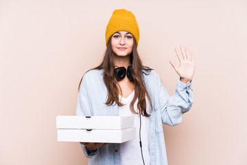 Young caucasian woman holding pizzas isolated smiling cheerful showing number five with fingers.