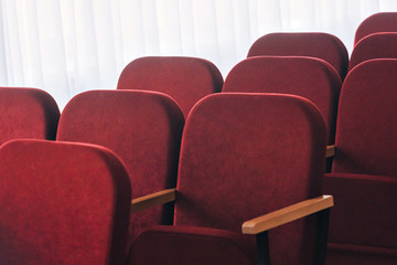 Fototapeta premium there are a lot of old chairs without people in the hall for performances and movies. in the frame fragments of the back of red seats with wooden handles.