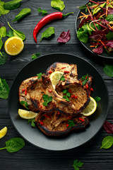 Homemade Grilled Pork loin chops in lemon sauce with herbs on rustic wooden table