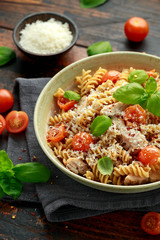 Healthy Chicken, fusilli pasta with tomatoes, basil and parmesan cheese. on wooden table.