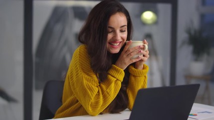 Closeup business woman looking laptop. Smiling girl drinking tea near notebook - Powered by Adobe