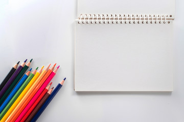 notepad with color pencil on white table view from above
