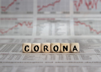 Corona word built with wooden cubes on a blured business newspaper background