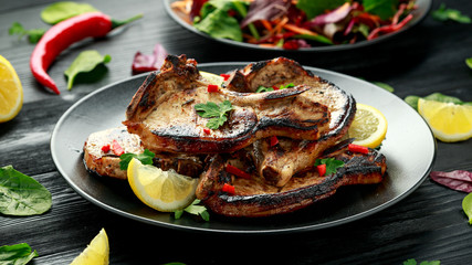 Homemade Grilled Pork loin chops in lemon sauce with herbs on rustic wooden table