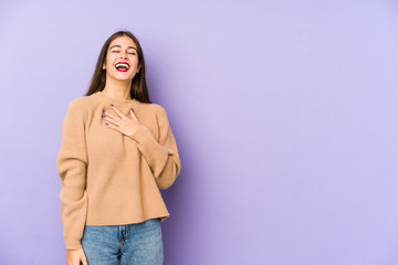 Young caucasian woman isolated on purple background laughs out loudly keeping hand on chest.