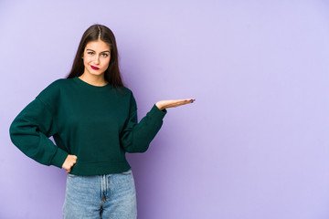 Young caucasian woman isolated on purple background doubting and shrugging shoulders in questioning...
