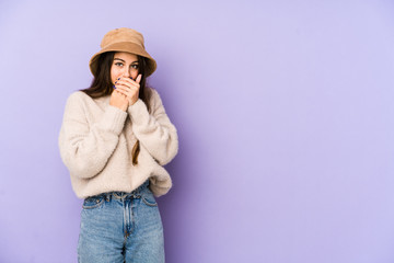 Young caucasian woman isolated on purple background covering mouth with hands looking worried.