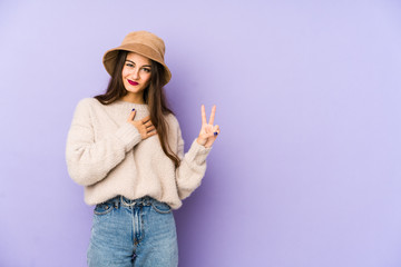 Young caucasian woman isolated on purple background taking an oath, putting hand on chest.